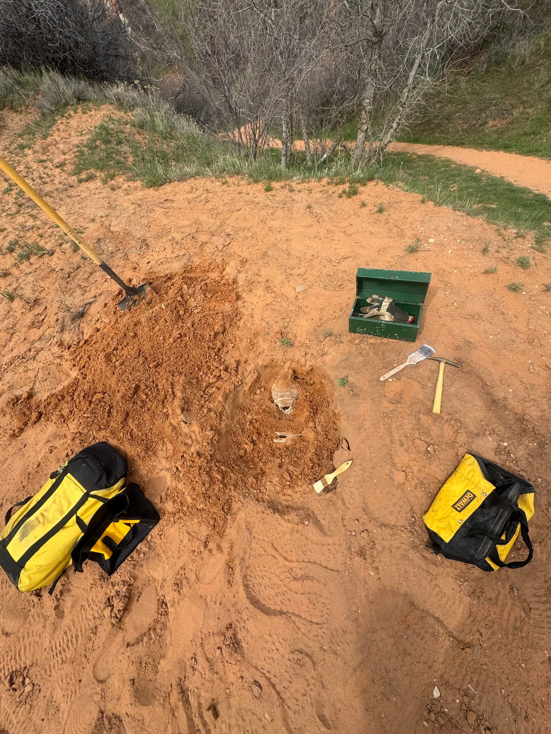 The dig site before a take: a hole in the red sand, a shovel, a pickaxe, a toolbox and gear bags