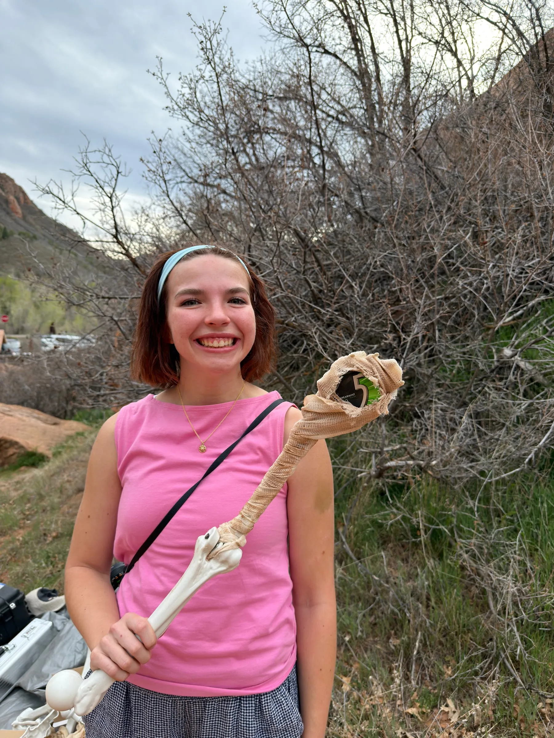 A crew member grins as she holds up the mummy's bandaged arm, the gum pack in its hand