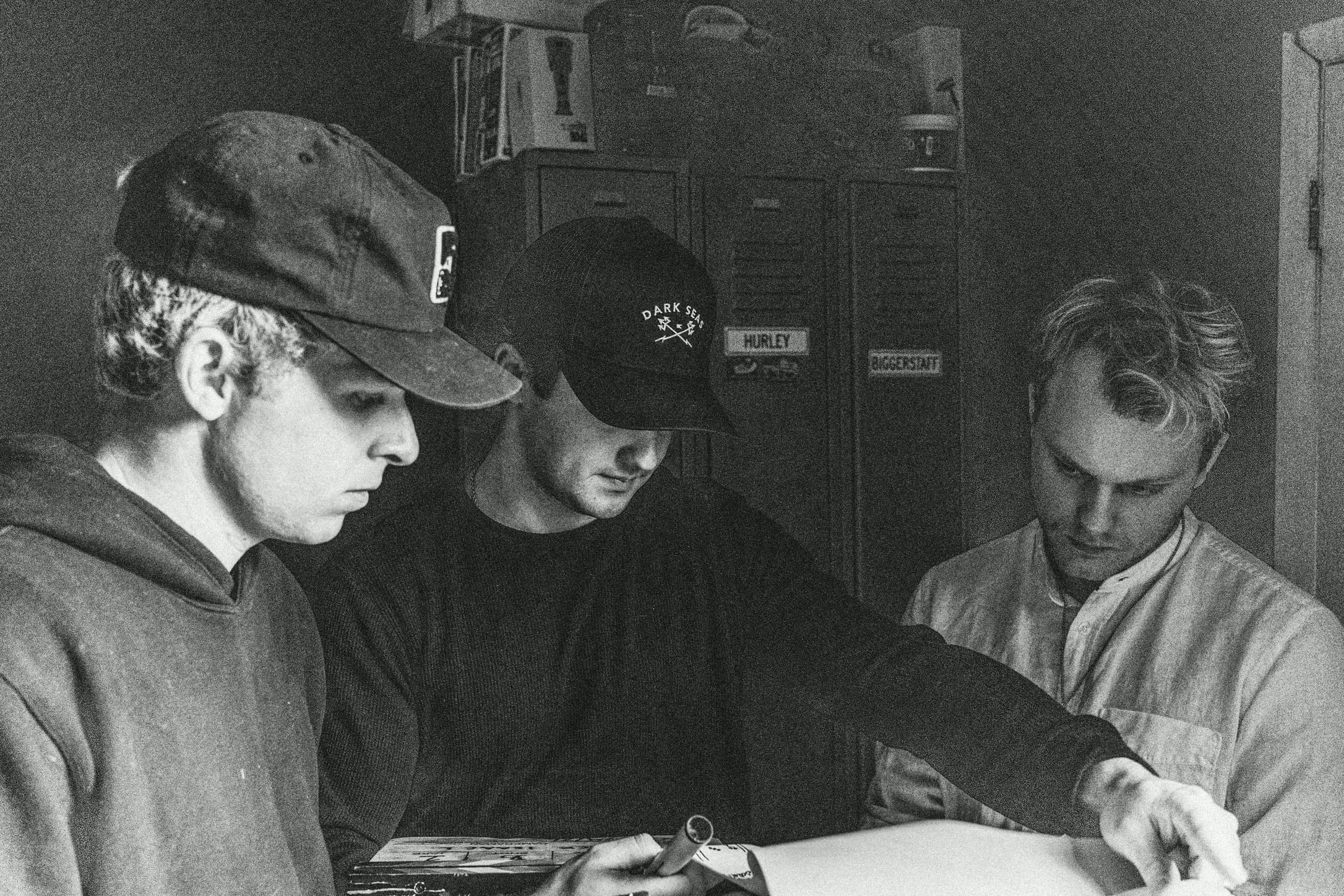 In black and white, three crew members go over a shot list at a table