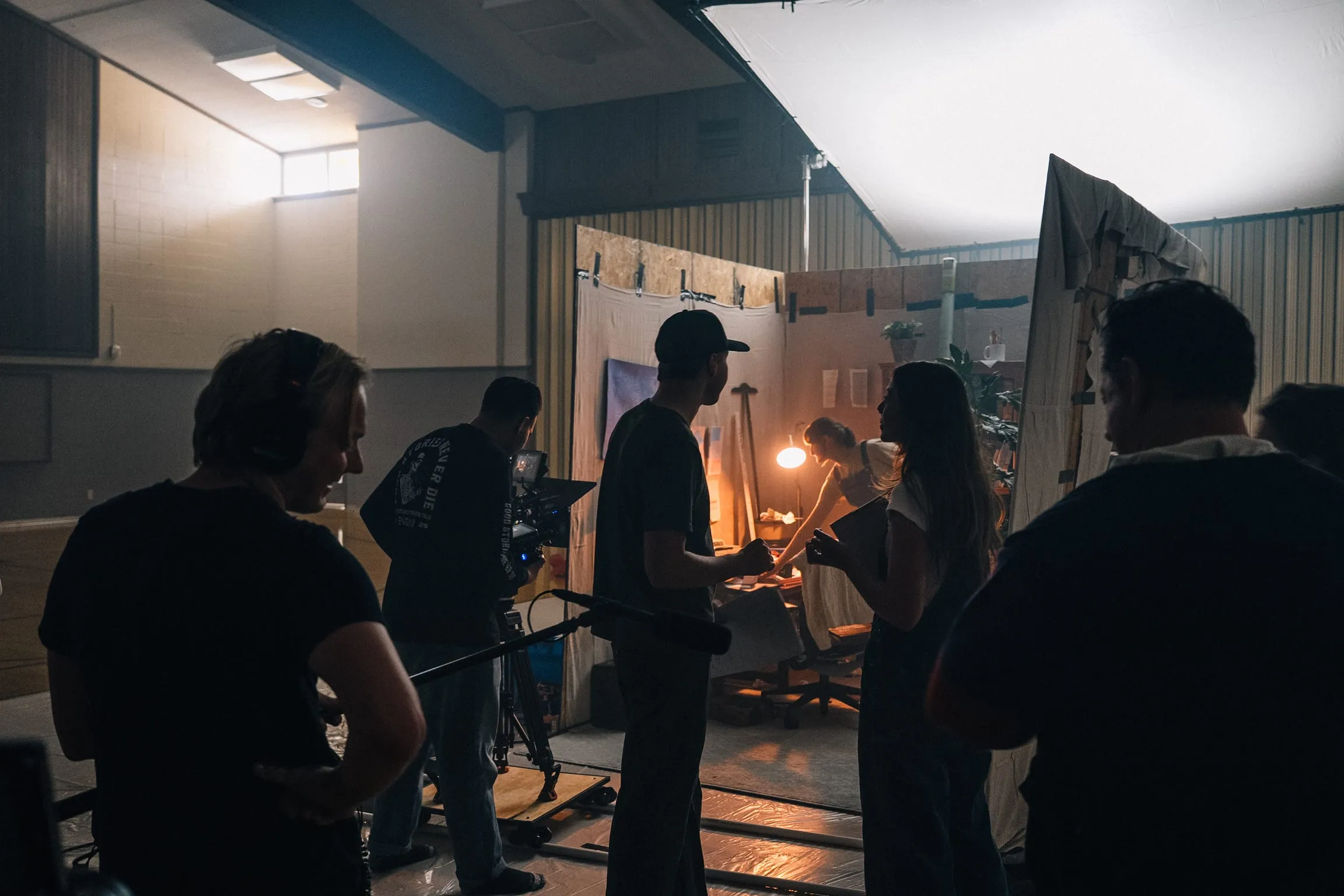 The crew gathers in silhouette at the warmly lit office set inside the hall