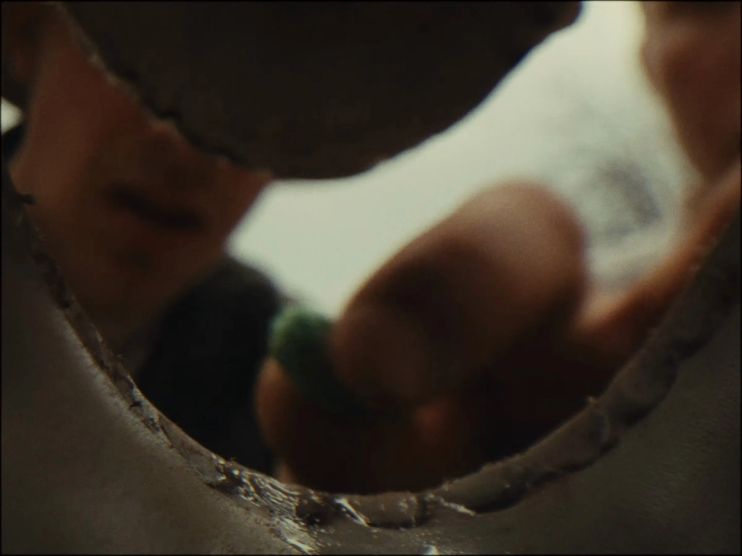 From inside a hole, blurred fingers reach in for a green piece of gum