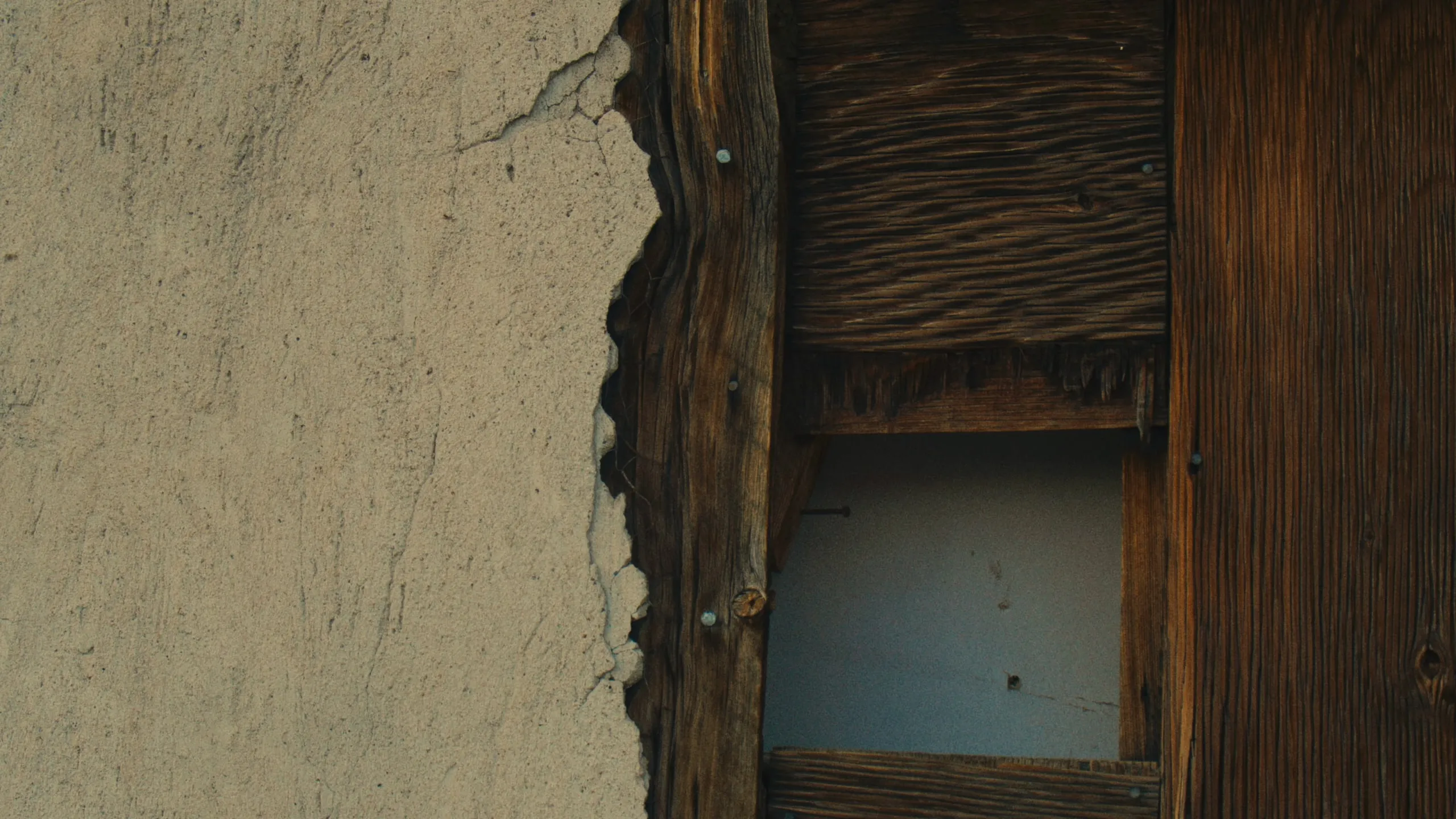 Cracked plaster and weathered boards on the abandoned house