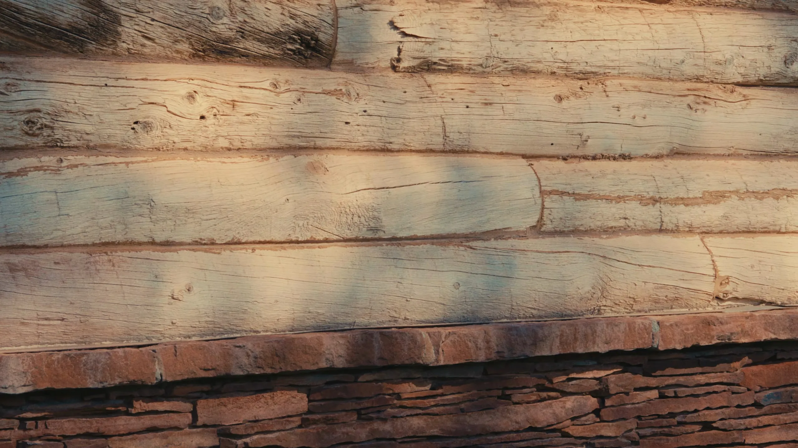 Low, warm light across a hand-hewn log wall