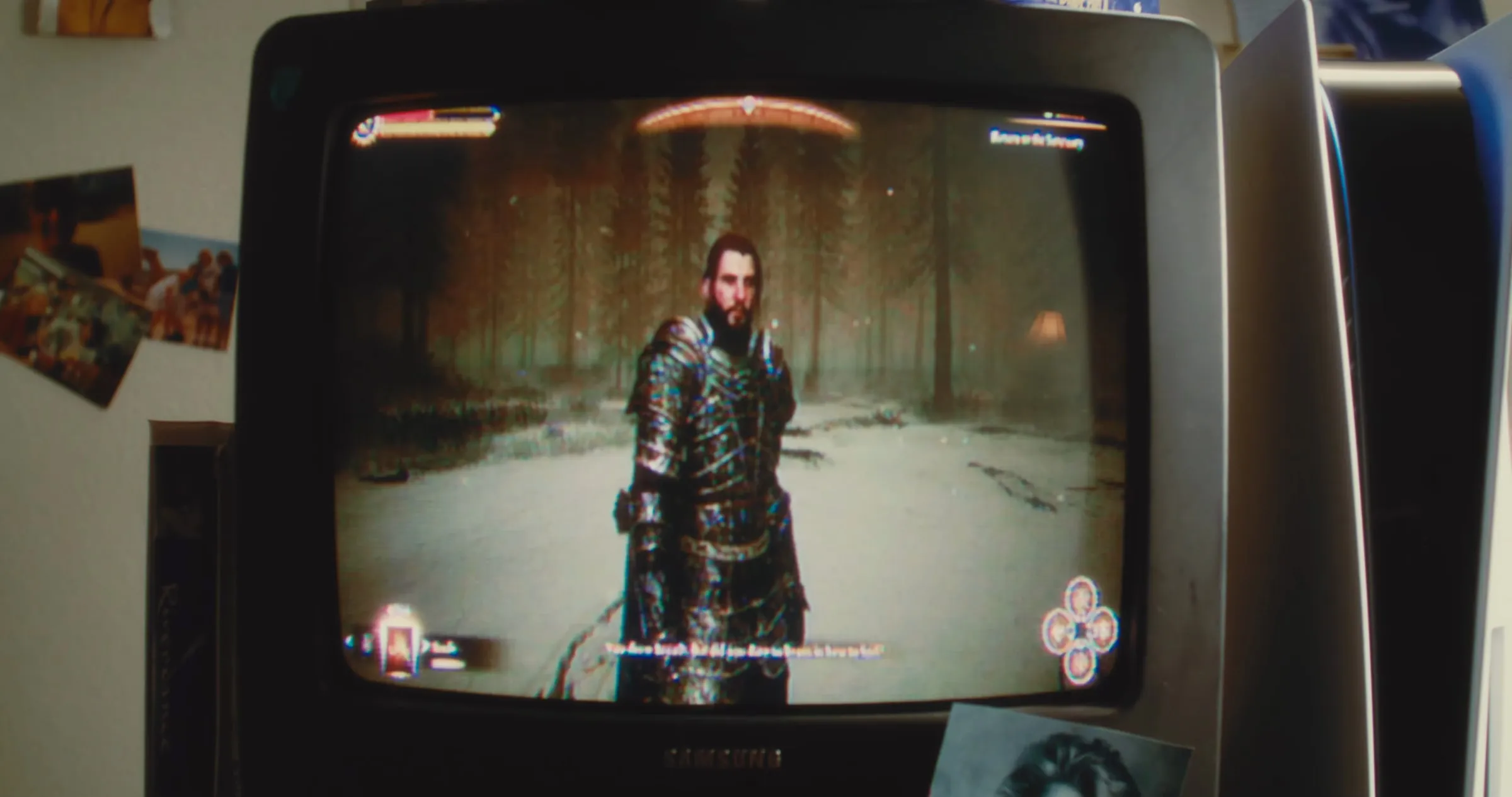 An armored knight in a snowy forest on an old tube TV, snapshots taped to the wall beside it