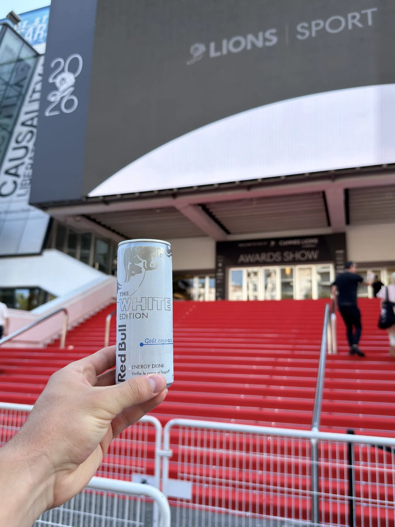 A White Edition can held up in front of the Palais in Cannes, the red steps of the awards show behind it
