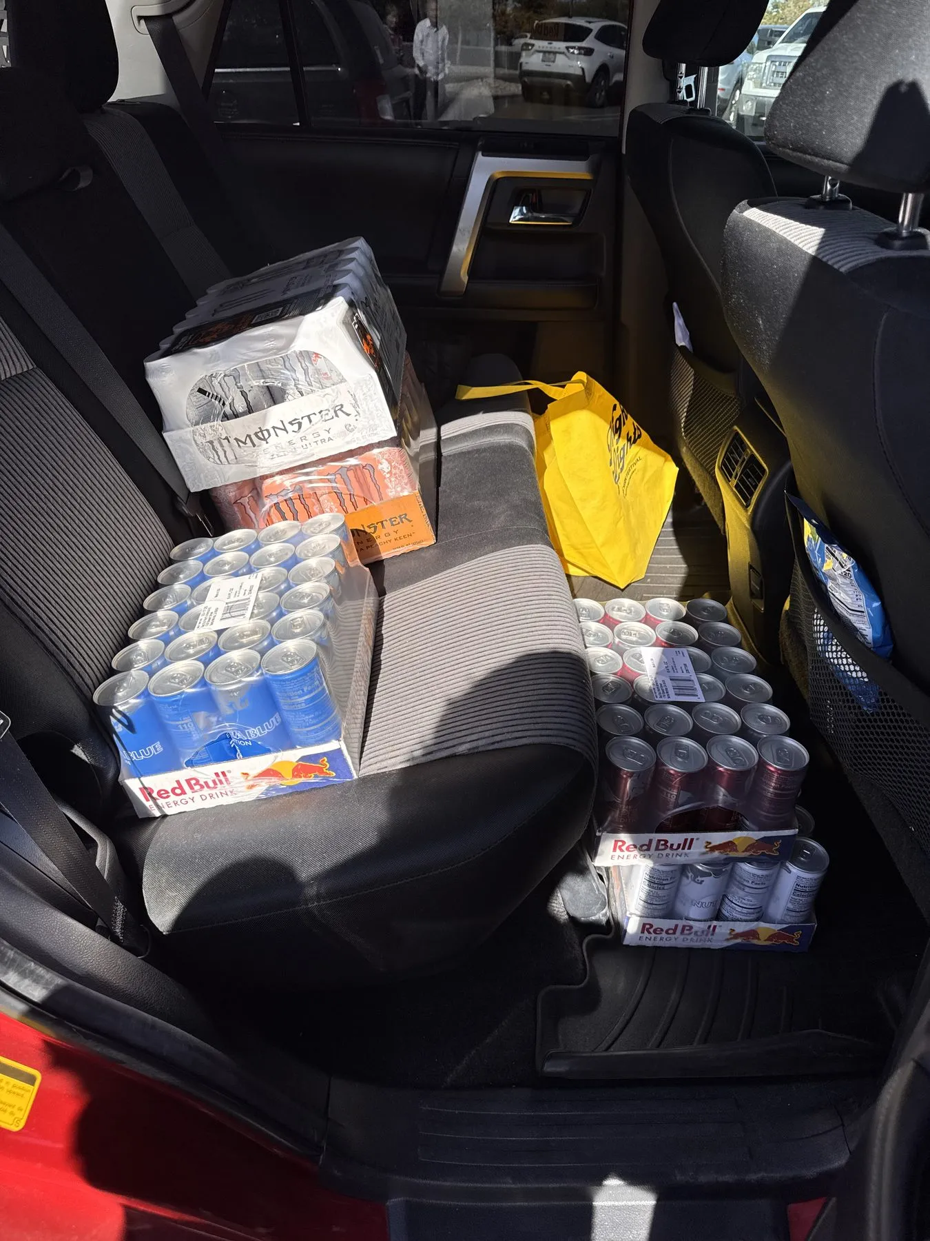 Flats of the Sea Blue, Peach and Coconut editions on the back seat and floor of a car, with two flats of Monster for a friend's birthday