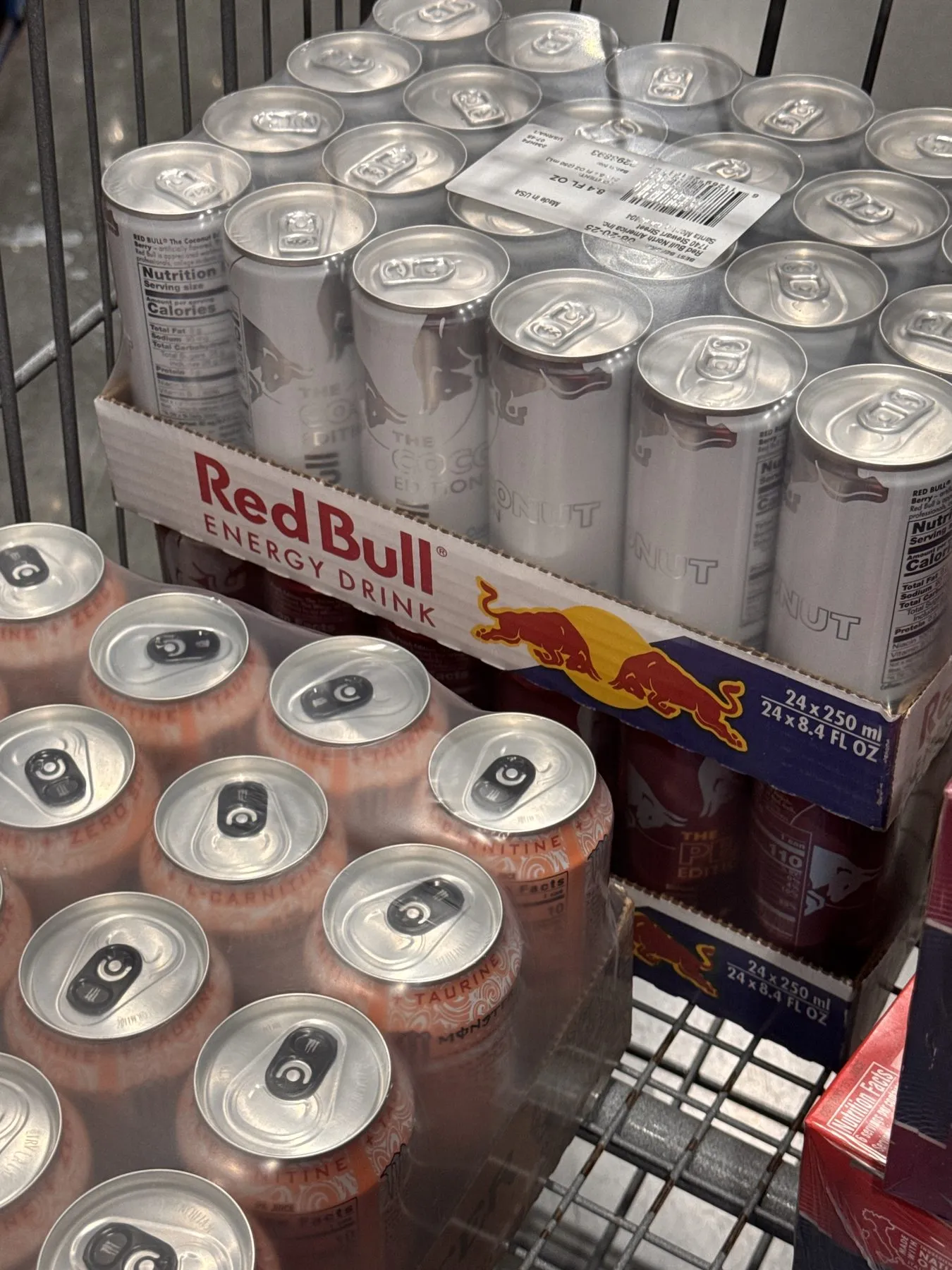 A Costco cart stacked with flats of the Coconut and Peach editions beside a flat of Monster for a friend's birthday