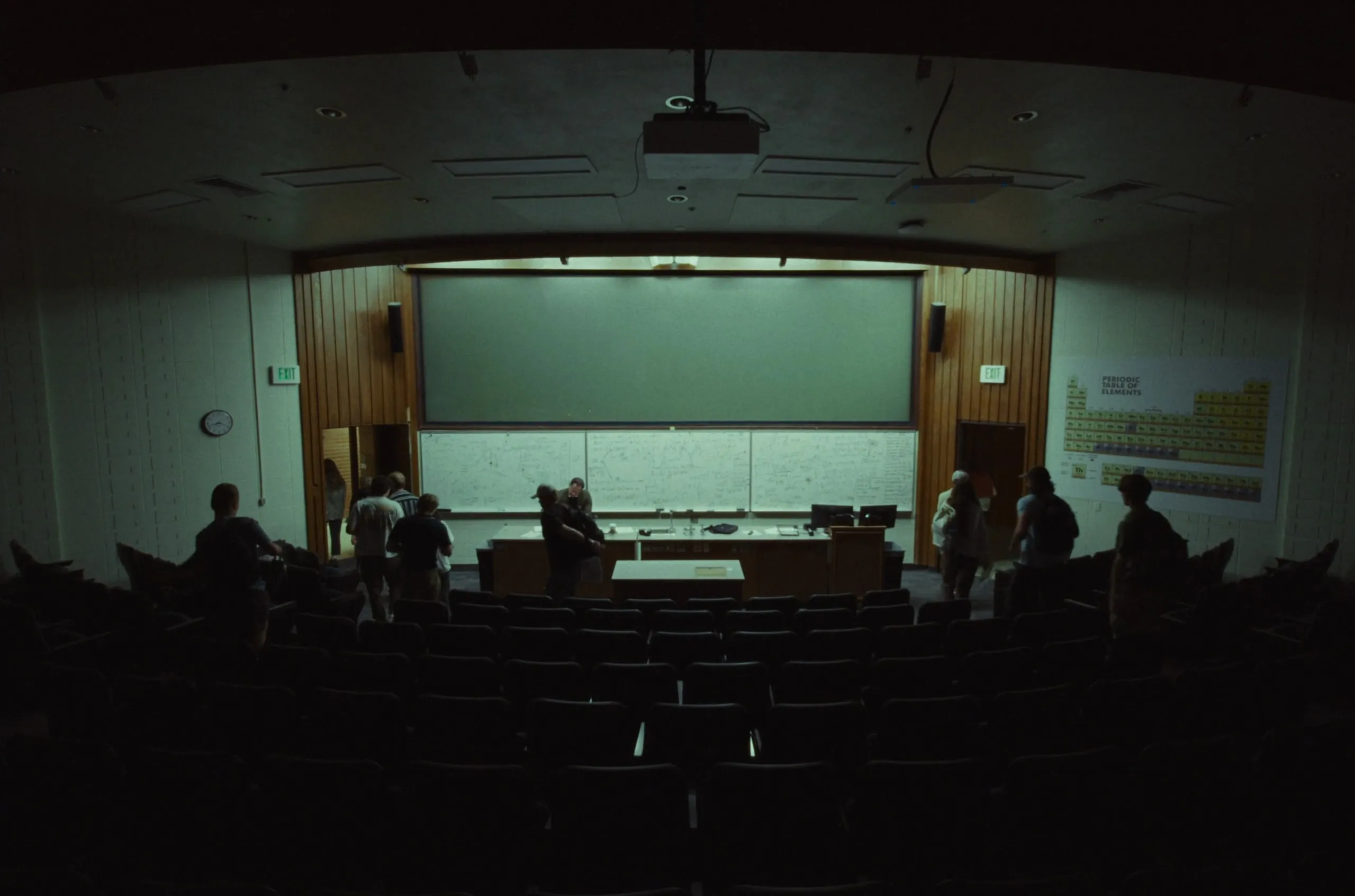 A lecture hall, nearly empty, a few students at the front