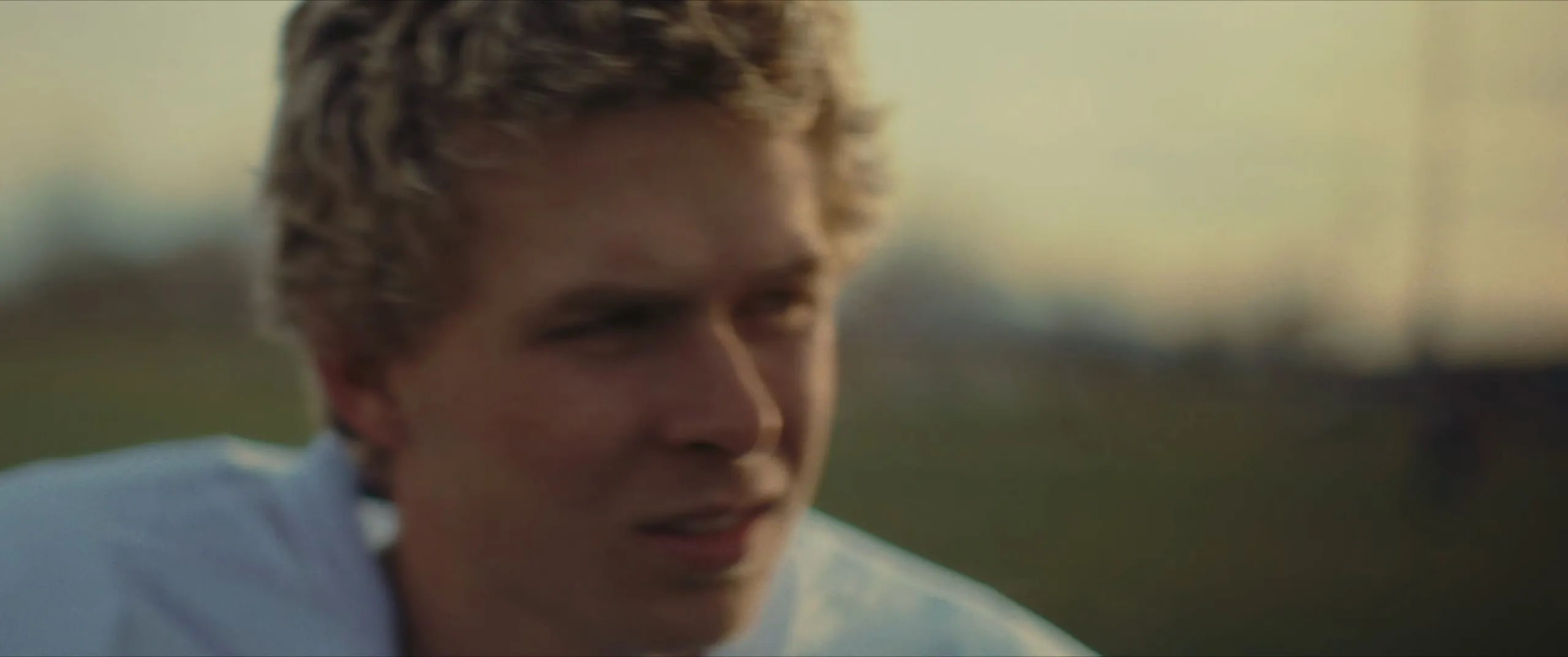 A young man looks off across a field at dusk
